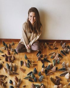 a woman is sitting on the floor surrounded by small pieces of bird feathers that are scattered around her