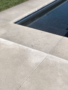 an empty swimming pool with grass in the background