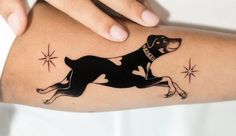 a woman's arm with a dog tattoo on it and stars in the background