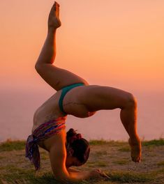 a woman doing a handstand in the grass