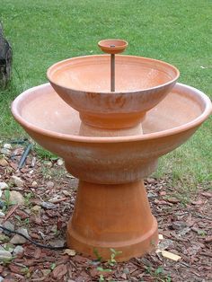 a large clay bowl sitting on top of a wooden stand in the middle of some grass