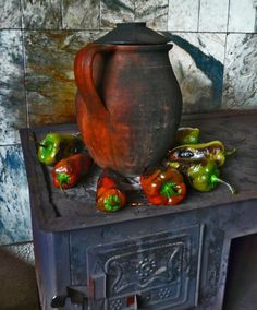 a pot sitting on top of an old stove with peppers around it and other items