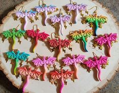 there are many different colored dragon shaped earrings on the tree slice that is sitting on the table