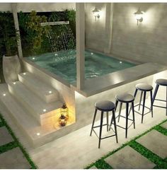 three stools sit in front of a pool with water running from the wall and lights on it