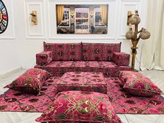 a living room filled with lots of pink couches next to a painting on the wall