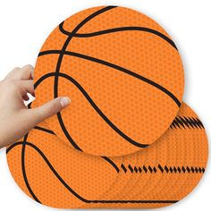 a hand pointing at an orange basketball on top of another one with black lines around it