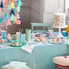 a blue table topped with lots of cake and cupcakes on top of it