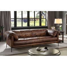 a brown leather couch sitting in front of a window