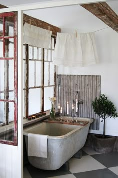 a bath tub sitting next to a window with curtains hanging from it's sides