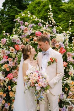 a bride and groom standing next to each other in front of a flower covered arch