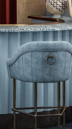 a blue bar stool sitting in front of a counter with a vase on top of it