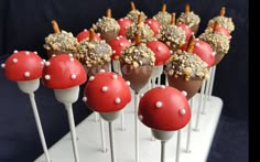 there are many red and white cake pops on the stick with candy toppings in them