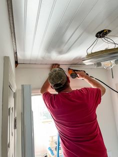 a man in red shirt working on a ceiling