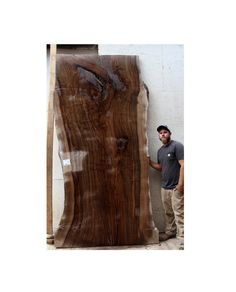 a man standing next to a large piece of wood