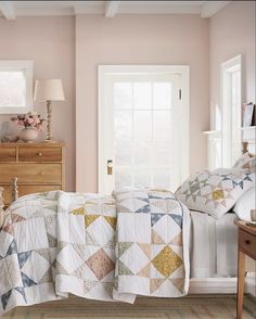 a bedroom with pink walls and quilts on the bedspread, two nightstands