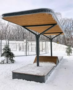 a wooden bench covered in snow next to a fence