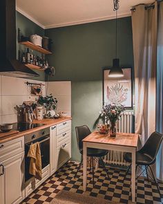 a kitchen with black and white checkered flooring next to a table in front of a window