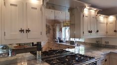 a kitchen with a stove top oven sitting next to a mirror on the side of it