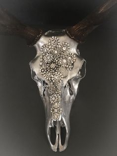 an animal skull with large horns and beads on it's back end, against a dark background