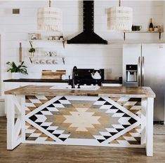 a kitchen with an island made out of wood and white painted tiles on the wall