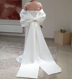 the back of a woman's white wedding dress with a large bow on it