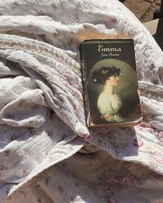 a book sitting on top of a bed covered in white sheets and pink flowered bedspread