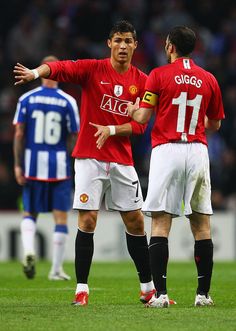 two soccer players in red and white uniforms on a field with one pointing at the other