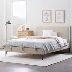 a white bed sitting on top of a hard wood floor next to a dresser and window