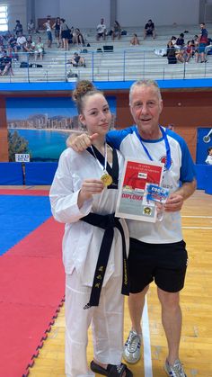 a man and woman standing next to each other on a wrestling court with medals in their hands