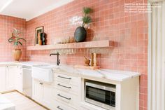 a kitchen with white cabinets and pink tiles on the wall, along with an oven