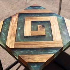 a table made out of wood and glass on top of a metal frame with a square in the center