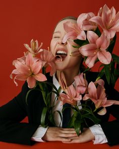 a woman with her mouth open and flowers in front of her face on a red background