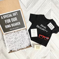 a black shirt and red sunglasses are in a cardboard box with the words ring bearer printed on it