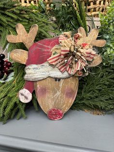 a wooden reindeer head sitting on top of a mantle next to evergreens and berries