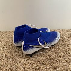 a pair of blue and white shoes sitting on top of a carpeted floor next to a wall