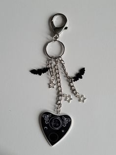 a black heart shaped keychain with stars and moon charms hanging from it's sides