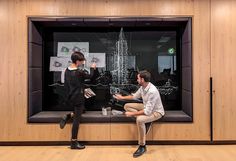 two people sitting on a bench in front of a window with an image of a tower