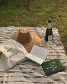 a bottle of wine and a book on a blanket in the grass next to a bottle of wine