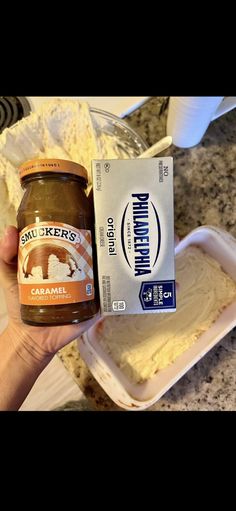 a person holding a jar of peanut butter next to a container of cake mix