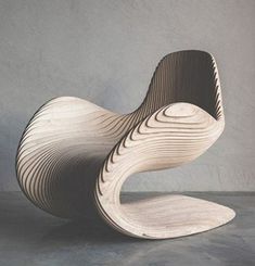 a wooden chair sitting on top of a cement floor next to a white wall in the background