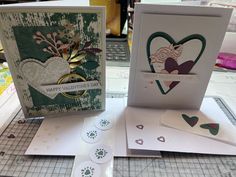 two cards with hearts on them sitting on top of a table next to some papers