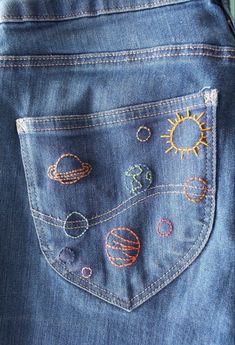 the back pocket of a pair of jeans with embroidered planets and sun patches on them