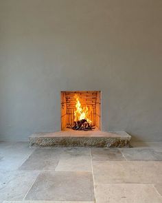 an open fire place in the middle of a room with tile flooring and walls