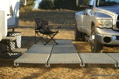 a truck parked next to a camper with a table and chairs on the ground