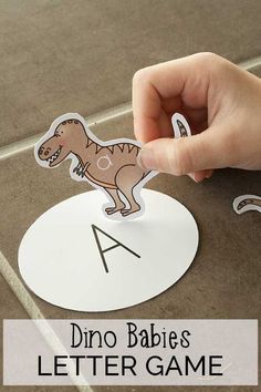 a hand holding up a dinosaur letter game