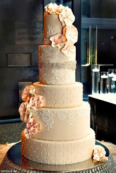 a three tiered wedding cake with flowers on the top and bottom, sitting on a silver platter