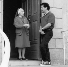 an old woman standing next to a man in front of a door