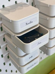 three white storage containers are stacked on top of each other and have labels reading needles