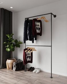 a clothes rack with shoes and sweaters hanging on it in front of a window