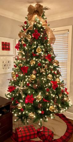 a christmas tree decorated with gold and red ornaments, bows, and baubles